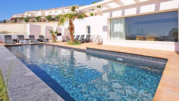 A modern pool area with clear water, lounge chairs, and a view of the surrounding buildings.