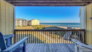A wooden deck with two chairs, overlooking a beach with buildings in the background. - Surf Condos 222 - Community Pool & Beach Bliss! (Surf City)