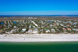 An aerial view of a coastal residential area with houses, a beach, and clear blue skies. - Island Dreams: Remodeled West Gulf Drive Pool Home (Sanibel)
