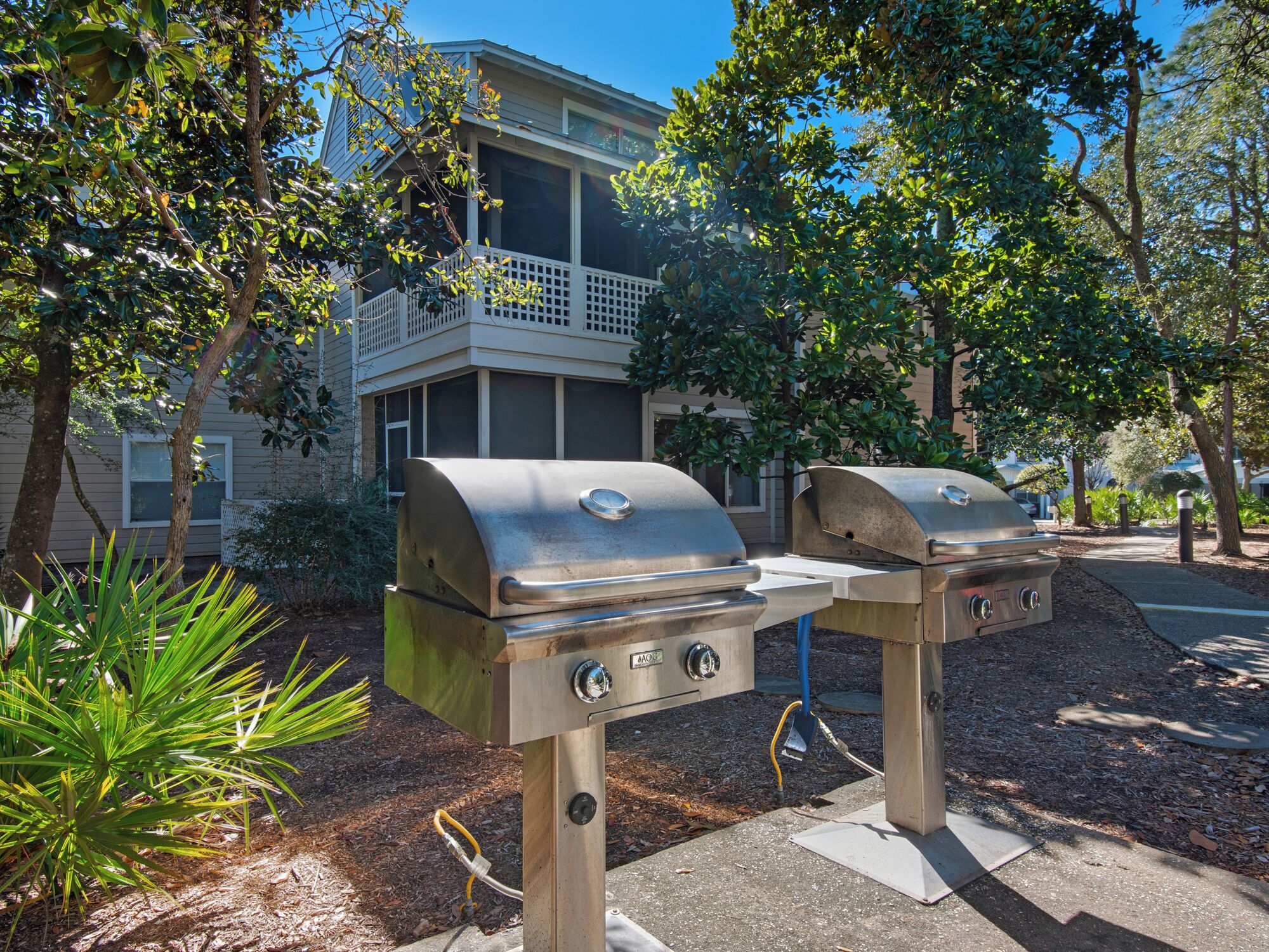 Deux barbecues installés dans un espace extérieur aménagé, avec un bâtiment en arrière-plan.