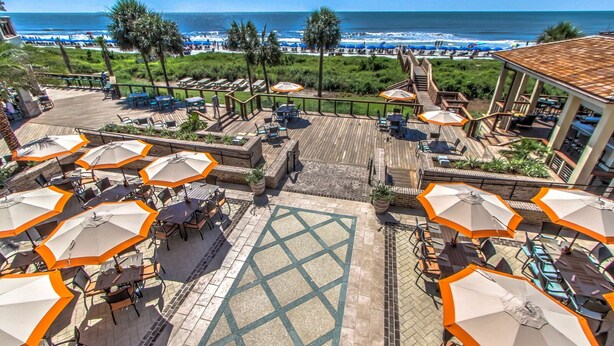 A rooftop patio with outdoor seating and umbrellas, overlooking a beach and ocean. - 1 Deer Run: Newly Listed & Furnished Home, Dog Friendly, 4 BR, Bikes (Hilton Head Island)