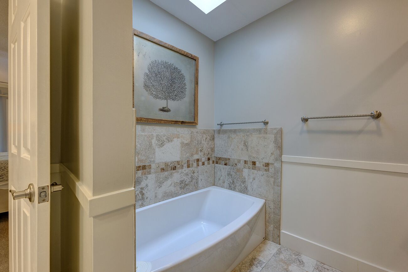 A bathroom with a freestanding bathtub, a towel rack, and a framed artwork on the wall.