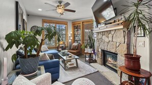 A living room with a fireplace, large windows, and a ceiling fan. - Downtown Breckenridge, Garage Parking! (Breckenridge)