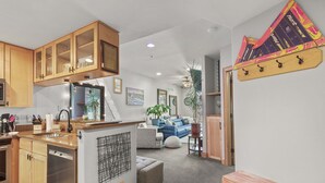 A modern kitchen with wooden cabinets, a built-in dishwasher, and a countertop with a sink. - Downtown Breckenridge, Garage Parking! (Breckenridge)