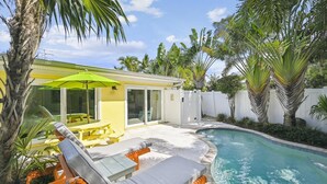 A backyard with a pool, outdoor furniture, and palm trees. - Holmes Beach Cottage Steps to the Beach with Heated Pool! (Holmes Beach)