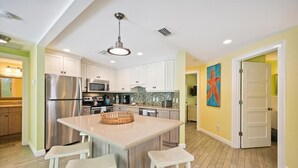 A modern kitchen with a central island, stainless steel appliances, and a bright color scheme. - Holmes Beach Cottage Steps to the Beach with Heated Pool! (Holmes Beach)