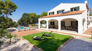 A two-story house with a patio, outdoor seating, and a swimming pool.