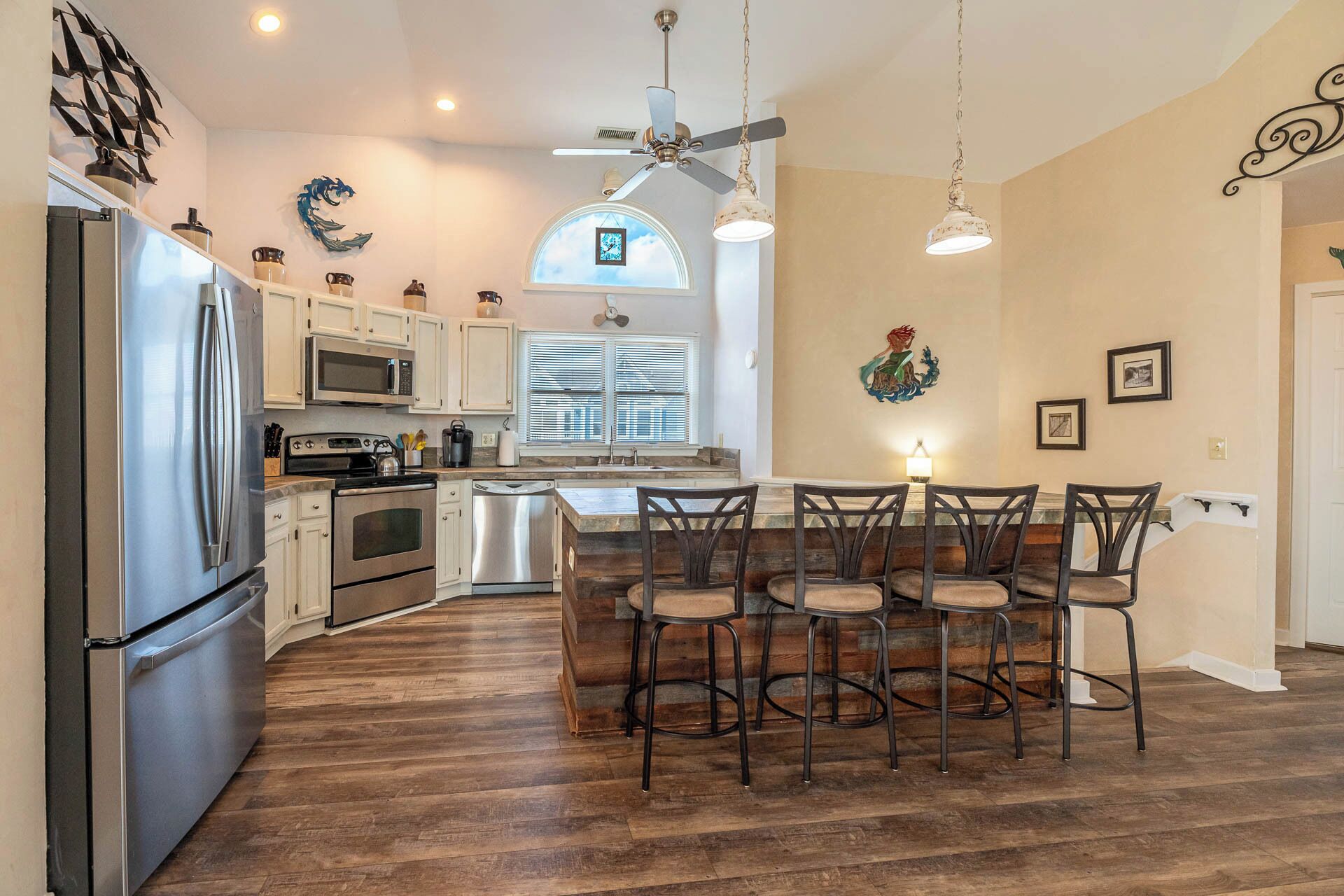 A kitchen with a central island, white cabinets, stainless steel appliances, and a dining area with wooden chairs.