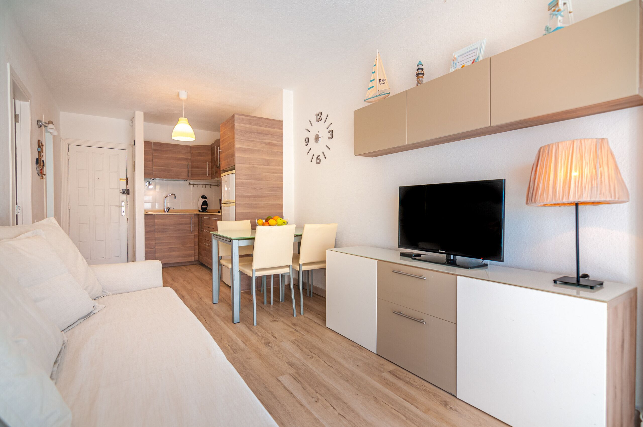 A modern, compact living space with a kitchenette, a dining area, and a TV.