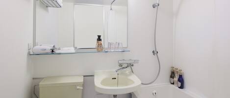 Une salle de bain comprenant des toilettes, un lavabo, un miroir, un porte-serviettes et une douche.