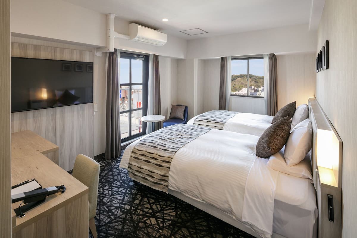 Een hotelkamer met een bed, een bureau, een stoel, een televisie en een raam met uitzicht.
