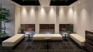 A modern lobby with a central seating area, dark tiled flooring, and recessed lighting. - H​OTEL MYSTAYS Kagoshima Tenmonkan Annex (Kagoshima)