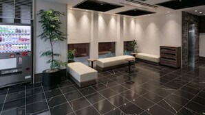 A modern lobby with a vending machine, seating areas, and a large potted plant. - H​OTEL MYSTAYS Kagoshima Tenmonkan Annex (Kagoshima)