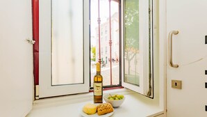 Asiento junto a la ventana con una botella de vino, un plato de pan y un bol de uvas.