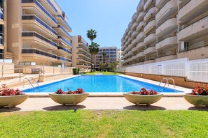 A swimming pool surrounded by apartment buildings, with a clear sky above.
