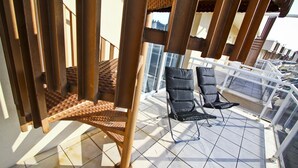 En balkon med gelændere, en stol og en liggestol.