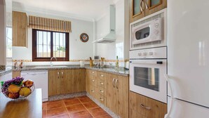 A kitchen with wooden cabinets, a built-in oven, a microwave, and a dishwasher. - Villa Jara - Three Bedroom Villa, Sleeps 6 (Nerja)