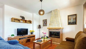 A living room with a TV, wooden shelves, a fireplace, and a sofa. - Villa Jara - Three Bedroom Villa, Sleeps 6 (Nerja)