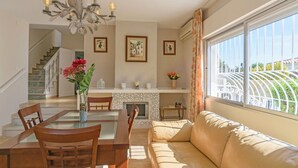A dining area with a chandelier, a fireplace, and a sofa by a large window. - Cubo's Villa Marieli Chilches / private pool / sea view / air conditioning / free wifi (Chilches Costa)