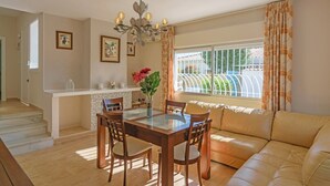 A dining area with a glass-top table, wooden chairs, a chandelier, and a sofa. - Cubo's Villa Marieli Chilches / private pool / sea view / air conditioning / free wifi (Chilches Costa)