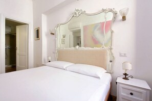 A neatly made bed with white linens, a large ornate mirror above it, a bedside lamp, and a small framed picture on the wall. - Rome, near Piazza di Spagna, cozy apartment for 6 (Rome)