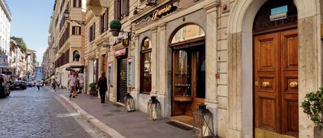 A cobblestone street with historic buildings, a shop named 'Penrose,' and a closed storefront.