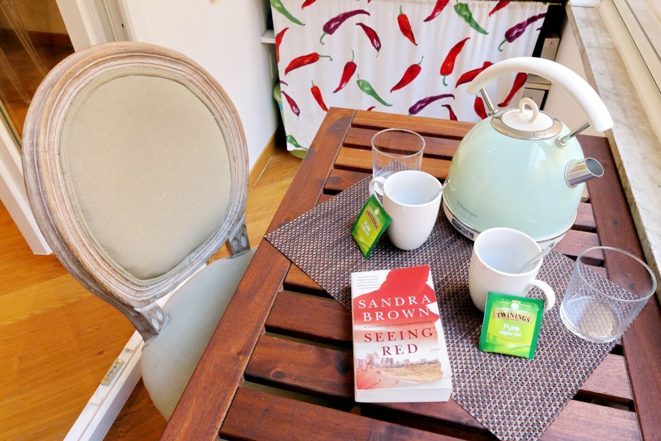 A wooden table with a teapot, cups, a book, and a packet of green tea.