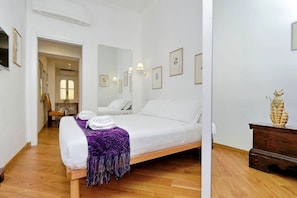 Ein Schlafzimmer mit einem Bett, Holzboden, einem Spiegel und einer Kommode.