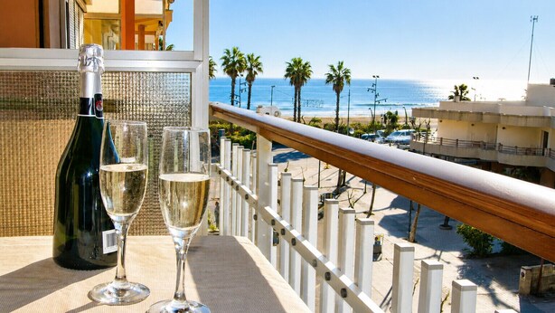 Een balkon met uitzicht op het strand, een fles wijn en twee glazen.