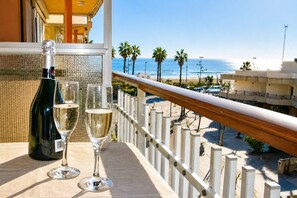 Un balcón con vista a la playa, una botella de vino y dos copas.