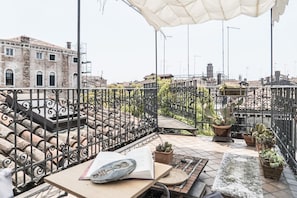 A rooftop terrace with a table, chairs, and potted plants. - Three Terraces (Venezia)