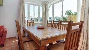 Ein Essbereich mit Holztisch und Stühlen, großen Fenstern und Blick auf Gebäude.