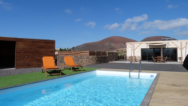 A swimming pool with lounge chairs, a wooden deck, and a view of mountains in the background.