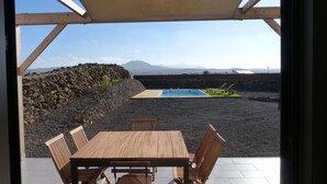 A covered outdoor seating area with a pool and a view of mountains.