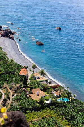 Une propriété située sur la côte, dotée d’une piscine, d’une plage et de formations rocheuses.
