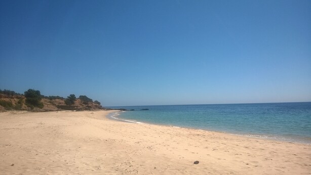 A sandy beach with clear blue water and rocky cliffs in the background. - Villa with garden surrounded by greenery a stone's throw from the sea (Santa Margherita di Pula)