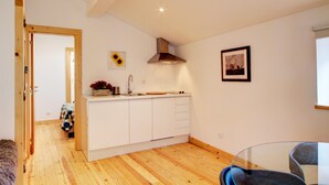 Een moderne keuken met witte kasten, een houten plafond en een inbouwfornuis.