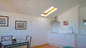 Een compacte keuken met een eethoek, dakraam en ingelijste foto's aan de muur.