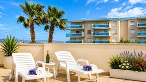 A terrace with two white lounge chairs, a small table with a bottle and glasses, and a potted plant. - LOS RISCOS (La Pineda)