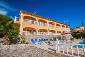 A hotel with a pool area, multiple balconies, and a stone-paved walkway. - Villa Zelda - PlusHolidays (Calpe)