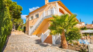 Un edificio de estilo mediterráneo con una escalera de piedra, una palmera y un cielo azul despejado.