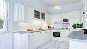 A modern kitchen with white cabinetry, a granite countertop, and a built-in oven. - Villa Polymnia (Kefalonia)