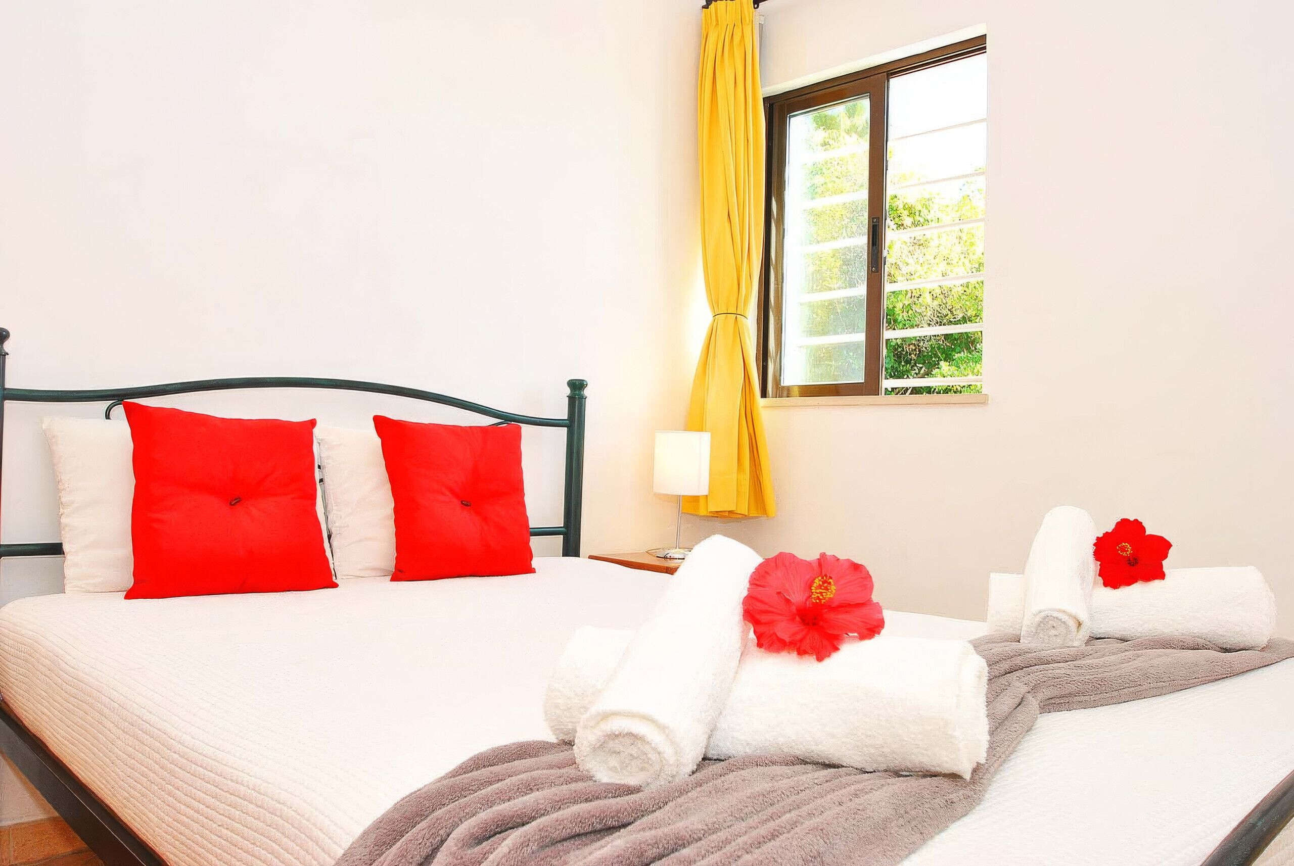 A hotel room with a bed, pillows, a window with curtains, and towels.