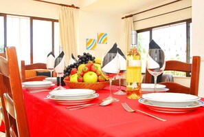 A dining table set with plates, cutlery, glasses, a fruit basket, and a bottle of wine. - Villa in Albufeira with Heated Pool & BBQ (Albufeira)