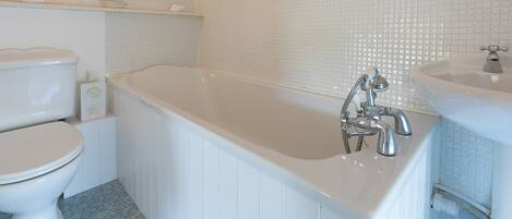 A bathroom with a white toilet, a bathtub with a chrome faucet, and a sink with a mirror.