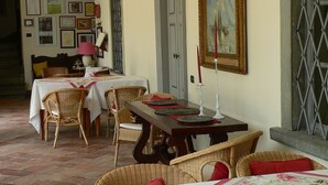 Un comedor con mobiliario de mimbre, una mesa con mantel blanco y cuadros en la pared.