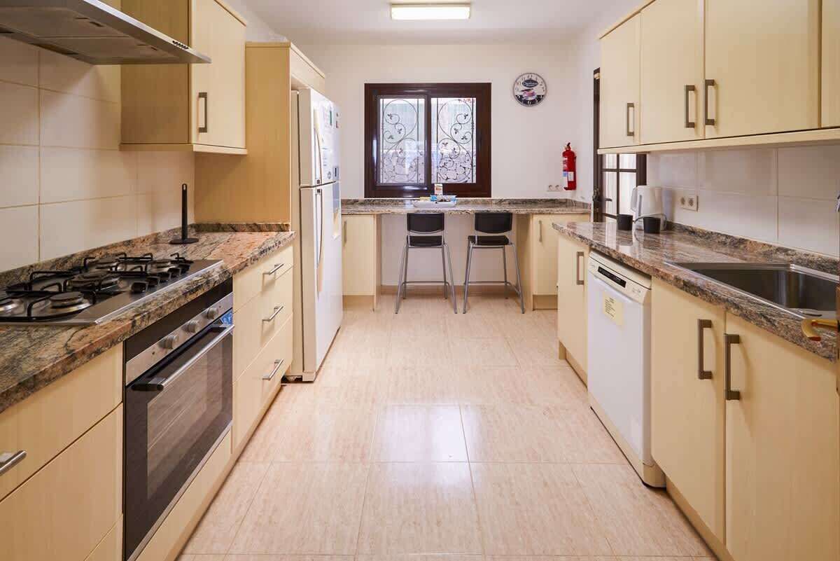 A kitchen with a gas stove, oven, and two bar stools.