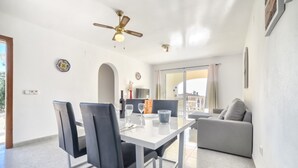 Ein moderner Essbereich mit einem weißen Tisch, schwarzen Stühlen und einem Deckenventilator.