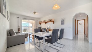 Ein moderner Essbereich mit einem weißen Tisch, schwarzen Stühlen und einer Pendelleuchte.