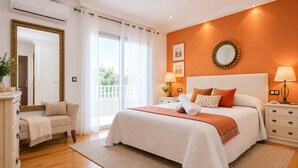 A hotel room with a large bed, a sitting area with a sofa, a dresser, and a large mirror. - Private swimming pool and jacuzzi in Cap Salou (Salou)